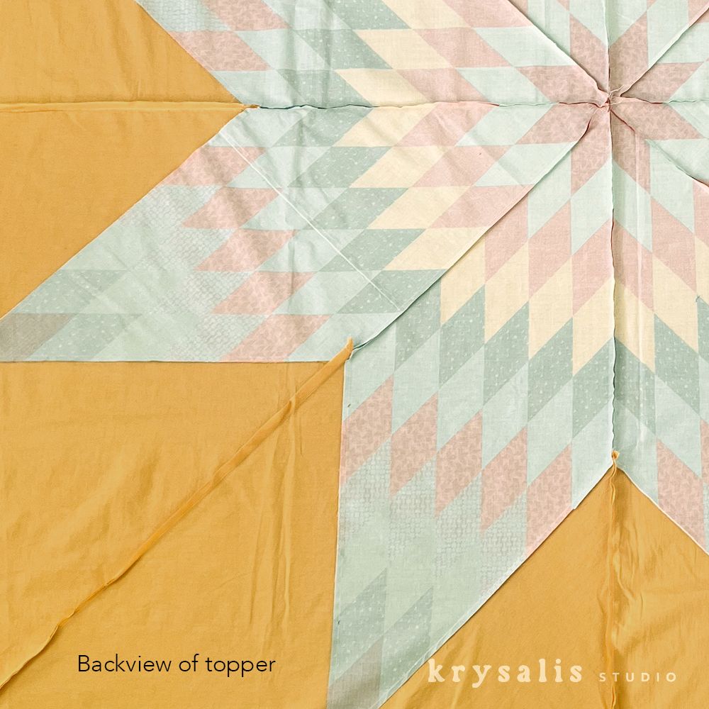 Back of the Lone Star quilt top, showing the pieced star seams against the mustard background